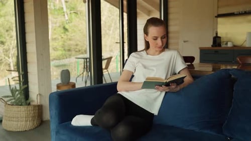 Woman Reading a Book on Couch Indoors