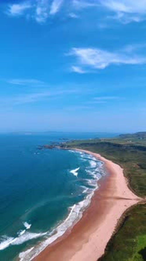 Splendid scenery of the Ireland shore on sunny day. Sandy beach with waves arriving to the coast