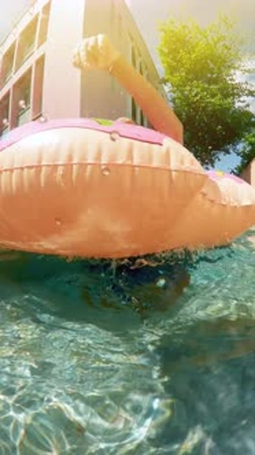 Young Woman Holding Breath Underwater in Swimming Pool is Looking Up at Surface