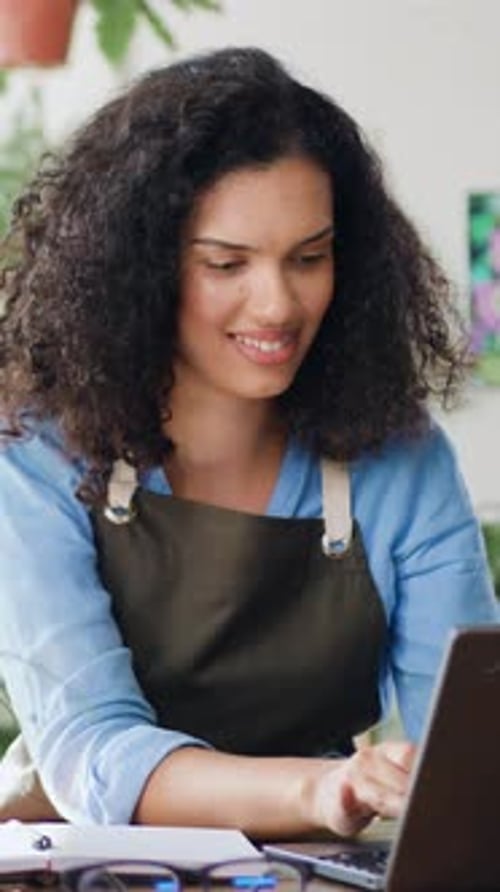 Young Afro American Woman Flower Business Owner in Apron Using Laptop Working at the Floral Store