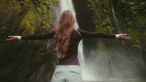 Woman Enjoying Beautiful Waterfall in Lush Green Nature