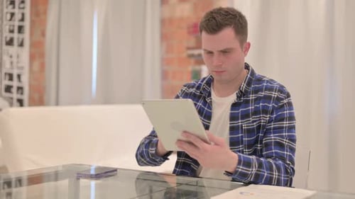 Man Reacts to Bad News on Tablet Indoors