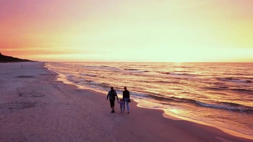 Happy Family Enjoying a Walk on a Beach at Sunset. Parents Walking With a Small Child. Sunset Beach