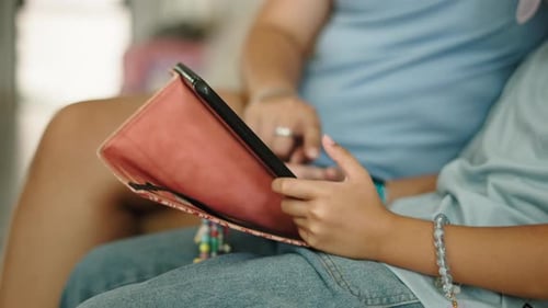 Closeup of a Mother and Little Girl's Hands Using a Tablet Together