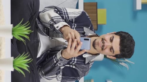 Vertical Video of Happy young man texting on the phone.
