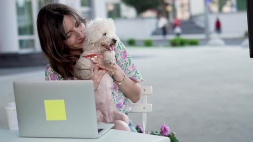 Happy Female with Cute Dog and Laptop in Outdoor Cafe