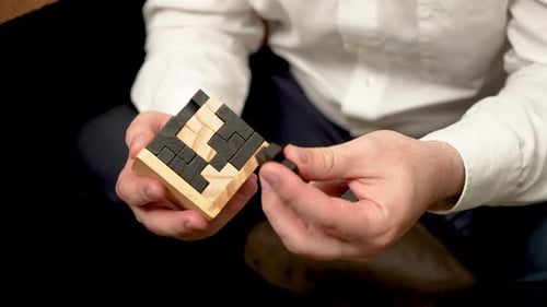 Un homme méconnaissable assemblant un puzzle fait de blocs pour entraîner ses capacités intellectuelles Gros plan sur un homme