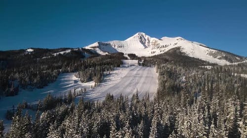 A drone shot of snowy Big Sky, Montana in winter, showcasing the ski resort and majestic mountain te