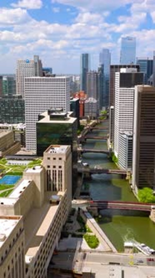River with numerous bridges coming through the city. Drone footage among the skyscrapers of Chicago