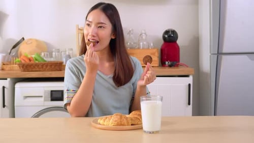 Woman Enjoying Cookies and Milk in Kitchen