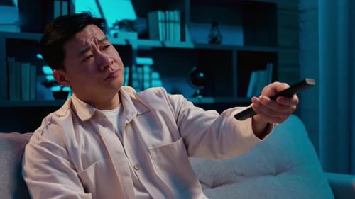 Upset Asian Middleaged Man Choosing Tv Channel Boring Cinema at Night Evening Insomnia at Home
