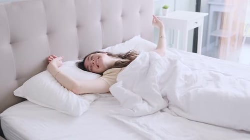 Woman Wakes Up and Stretches in Bed