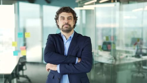 Confident Businessman Stands with Arms Crossed in Office