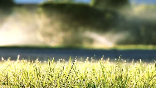 Focus pull from green grass to modern water sprinklers