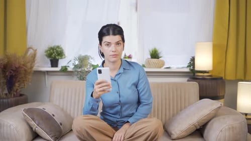 Woman Using Smartphone Sitting on Couch Indoors
