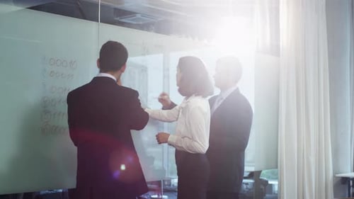 Ein Team von Büroangestellten diskutiert in der Nähe von Glass Whiteboard