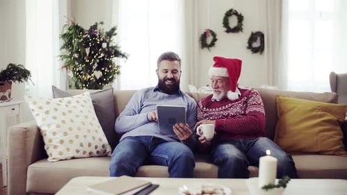 Two men using a tablet on the couch