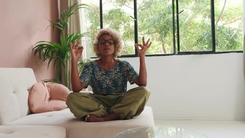 Woman Meditating in Lotus Position on Couch