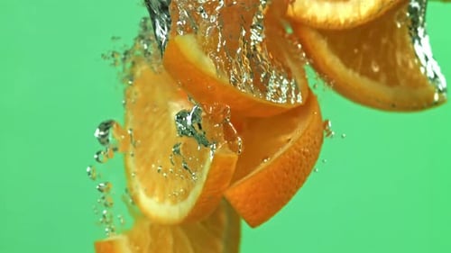 Orange Slices Falling Under Water on a Green Background Filmed on a Highspeed Camera at 1000 Fps