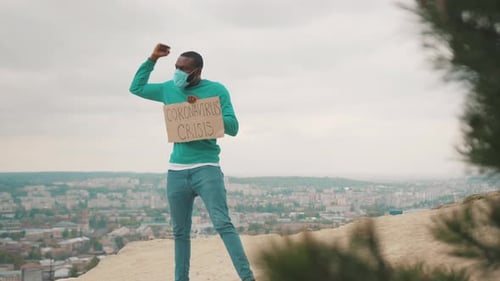 Adult Man Stands With Sign on Hill Overlooking City