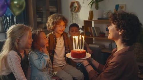 Birthday Boy Making Wish and Blowing out Candles on Cake at Party