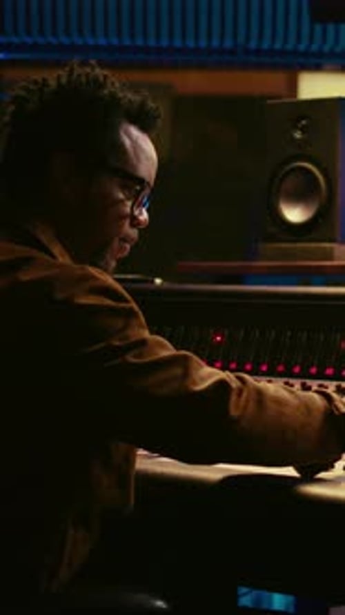 Man Adjusts Soundboard in Recording Music Studio