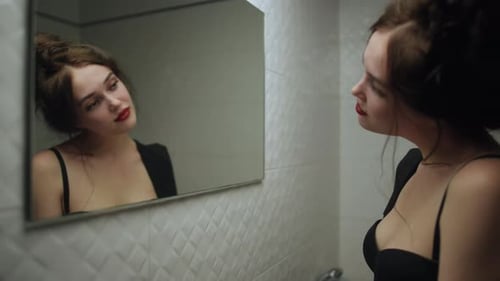 Young Woman Looking in Mirror in Bathroom