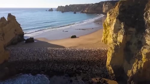 Aerial or a drone shot over some mountains and cliffs in Portugal while the sun is shining during th