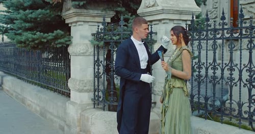 Elegant Couple Chatting Next to Decorative Fence
