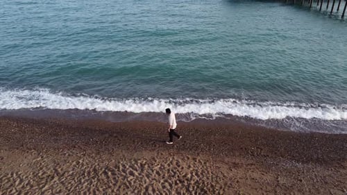 Aerial view of young man walking on the beach 4K