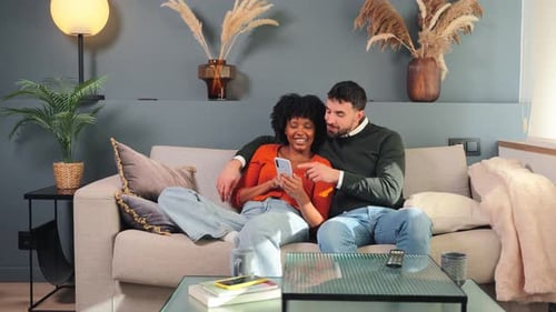Happy Couple Relaxing on Sofa Sharing Smartphone
