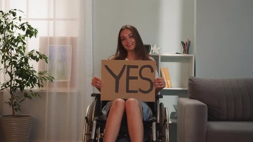Smiling Woman in Wheelchair Holds Yes Sign