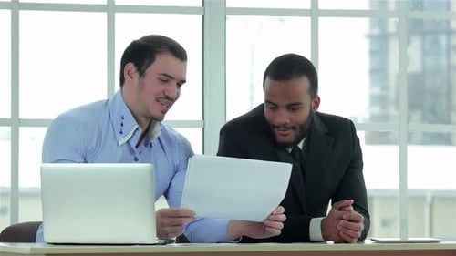 Dynamic Collaboration Between Two Confident Businessmen in a Modern Office