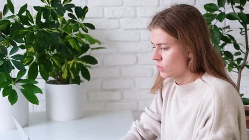 millennial woman using laptop for work sitting at table at home