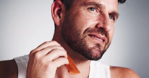 Studio, grooming and man with beard, comb and smile for fresh shave, routine and facial treatment