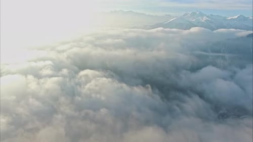 Clouds below the high peaks of the Alps with a sunny atmosphere