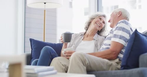 Older Couple Laughing Together at Home on Sofa