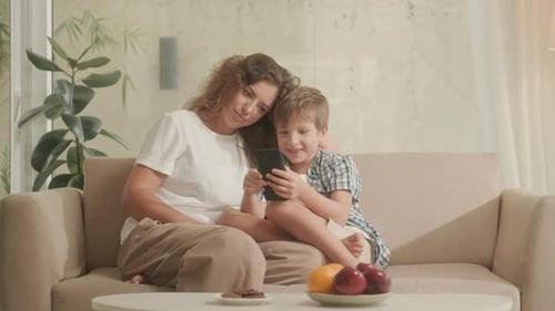 Mother and Son Watching Smartphone Together on Couch