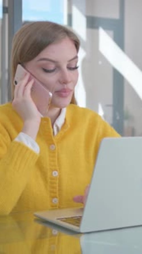 Woman Working at Laptop and Talking on Phone