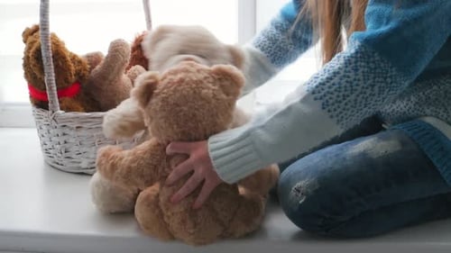 Child Cuddling Teddy Bear on Window Seat