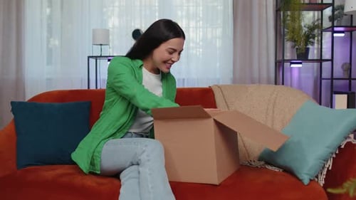 Woman Excitedly Opening Box on Couch
