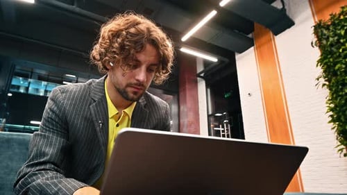 Young Adult Working on Laptop in Modern Office