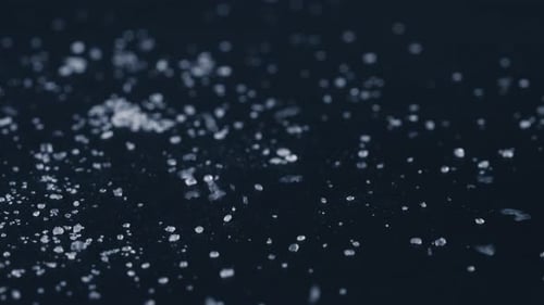 Nahaufnahme auf schwarzblauem Hintergrund weißer, krümeliger Kristallzucker liegt darauf, Kristallklumpen um einen