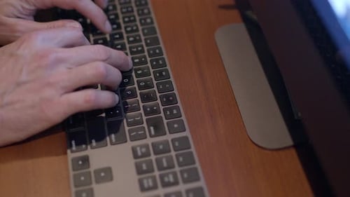 Hands Typing on Computer Keyboard at Desk