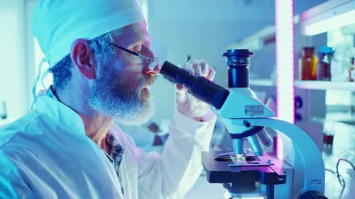 Adult Man Using Microscope in Brightly Lit Lab