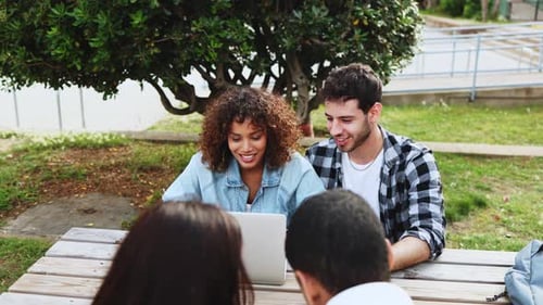 Diverse students working together on laptop in outdoor setting