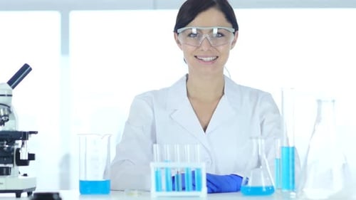 Smiling Successful Female Scientist Sitting in Laboratory Looking at Camera