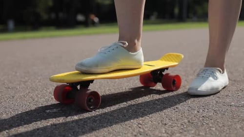 Teenage girl riding short modern skateboard on a road in summer for fun