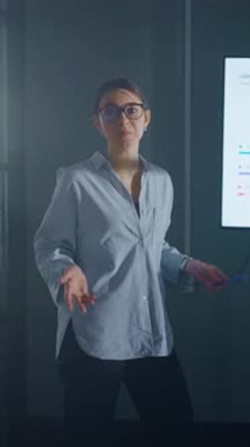 Confident Businesswoman Presenting Financial Analytics and Colorful Bar Charts on Large Screen