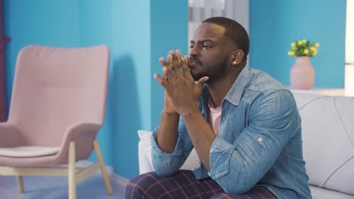Man Sitting and Thinking Indoors with a Sad Expression
